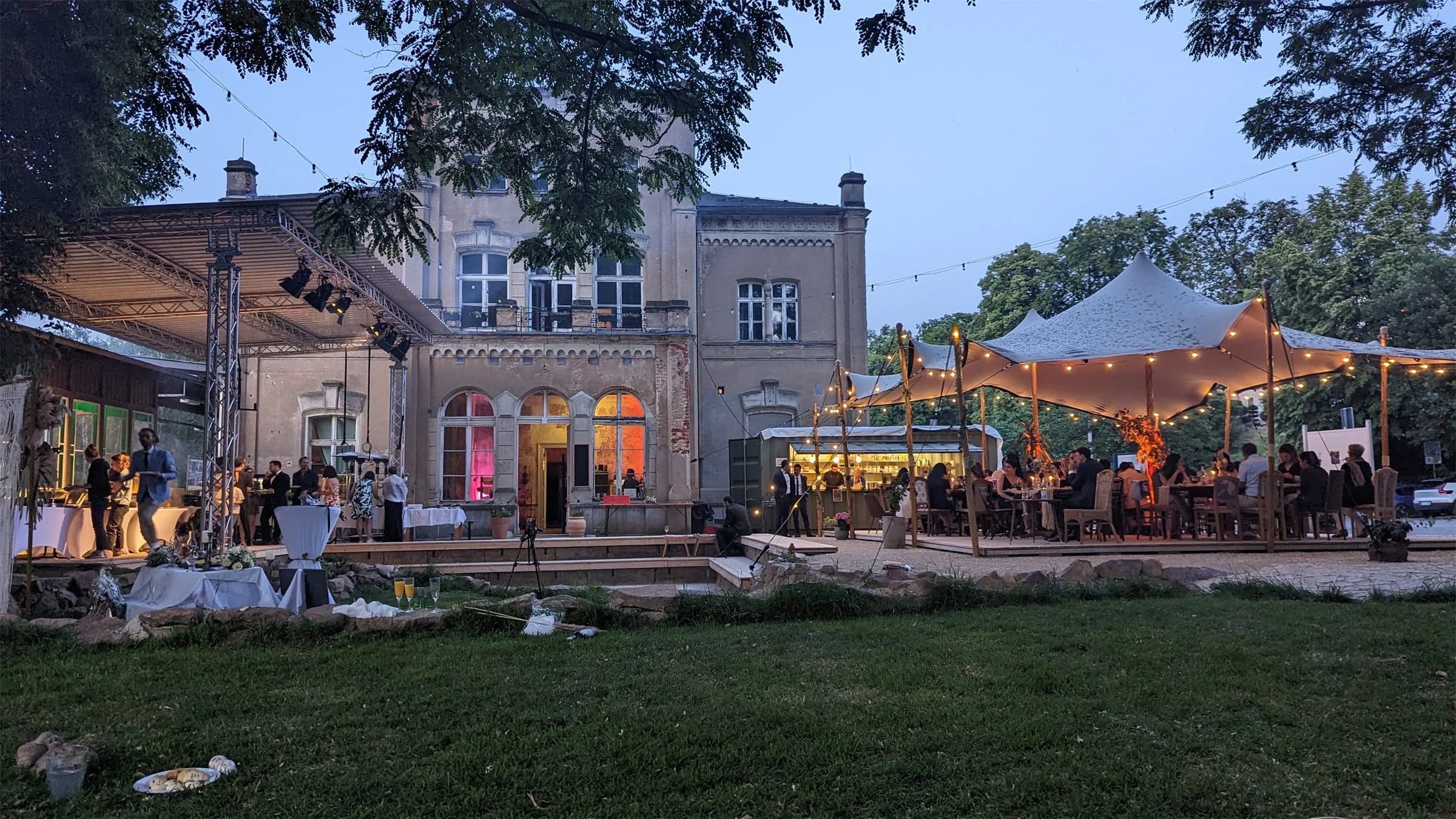 Der Kulturbahnhof Leisnig bei Dämmerung mit beleuchtetem Zelt im Garten